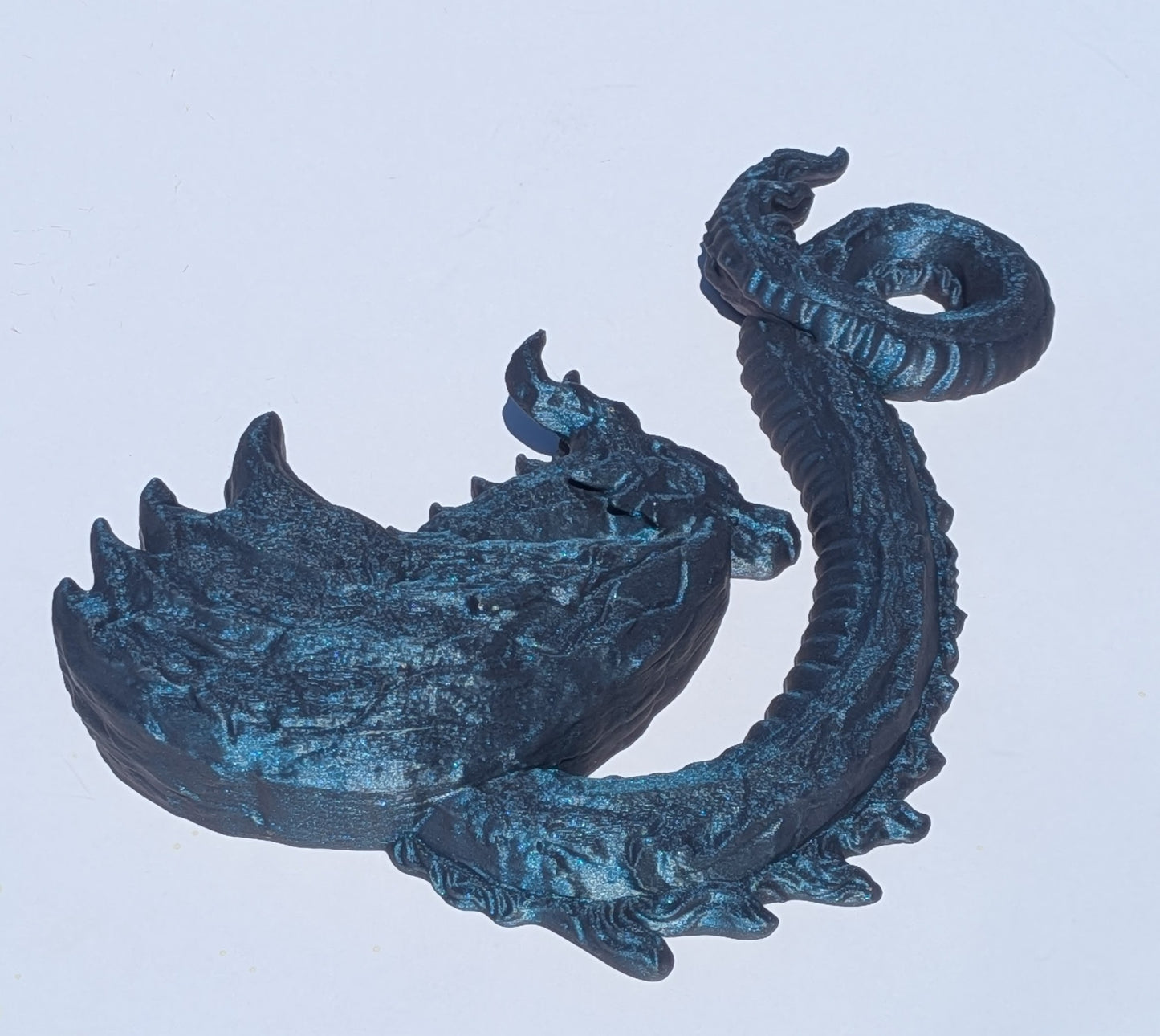 A dark metallic blue dragon figurine with a textured, weathered finish, shown against a plain light gray background.