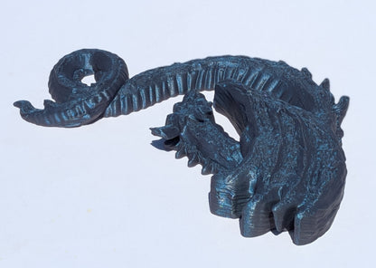 A dark metallic blue-gray 3D-printed dragon figurine, shown from a side profile against a plain white background.