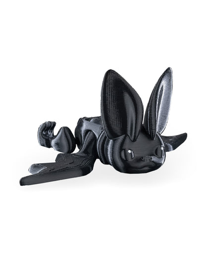 Black articulated bat fidget toy lying on its side with wings folded