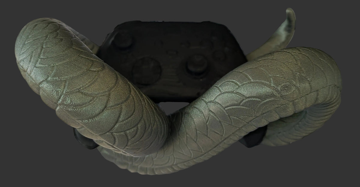 A textured olive green snake toy draped over a black VR headset, set against a black wire grid backdrop with a faux brick pattern.