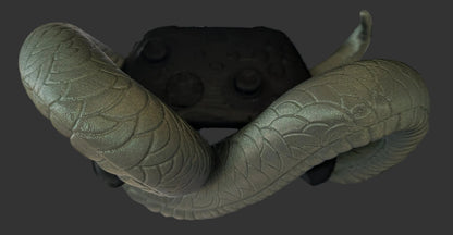 A textured olive green snake toy draped over a black VR headset, set against a black wire grid backdrop with a faux brick pattern.