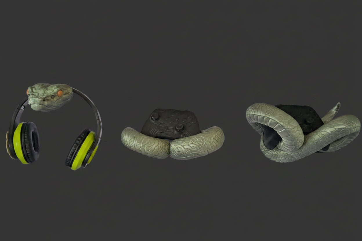 A black metal wire grid wall rack mounted on a gray brick-patterned wall, holding various items including lime green and black over-ear headphones, a gray textured pad, a gray snake-shaped object, and a brown leather item at the bottom.