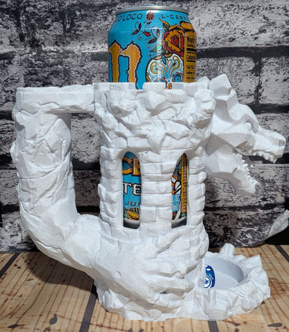 A white dragon-shaped mug or drink holder made of textured material, with a colorful beverage can inserted into its body, set against a gray brick wall background.