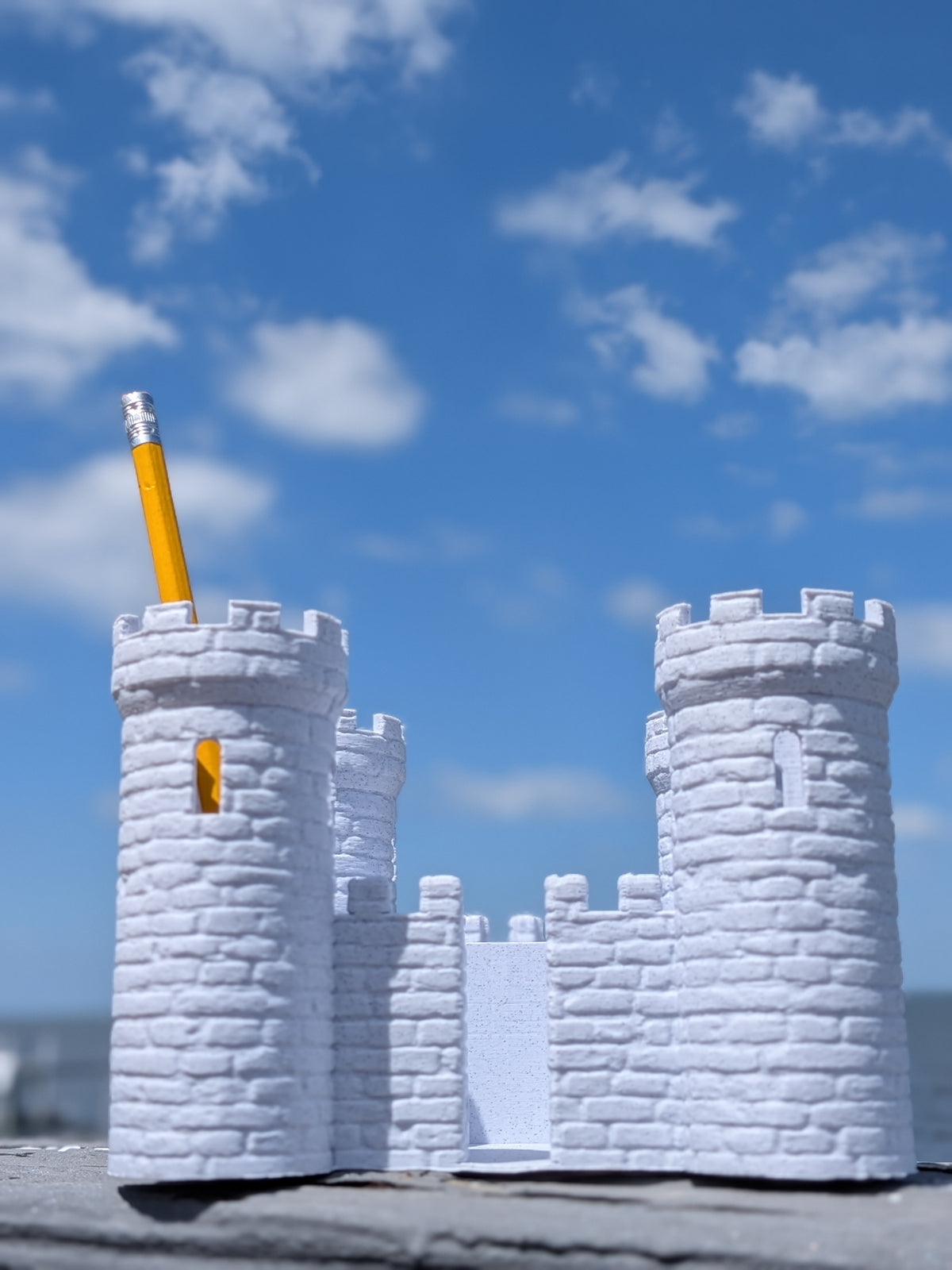 Castle-shaped desk organizer holding a pencil in one turret, outdoor photo