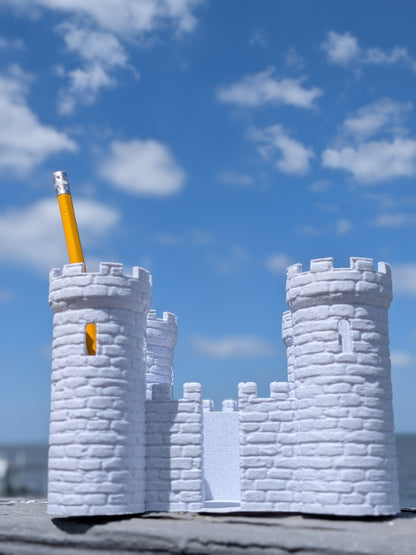 Castle-shaped desk organizer holding a pencil in one turret, outdoor photo
