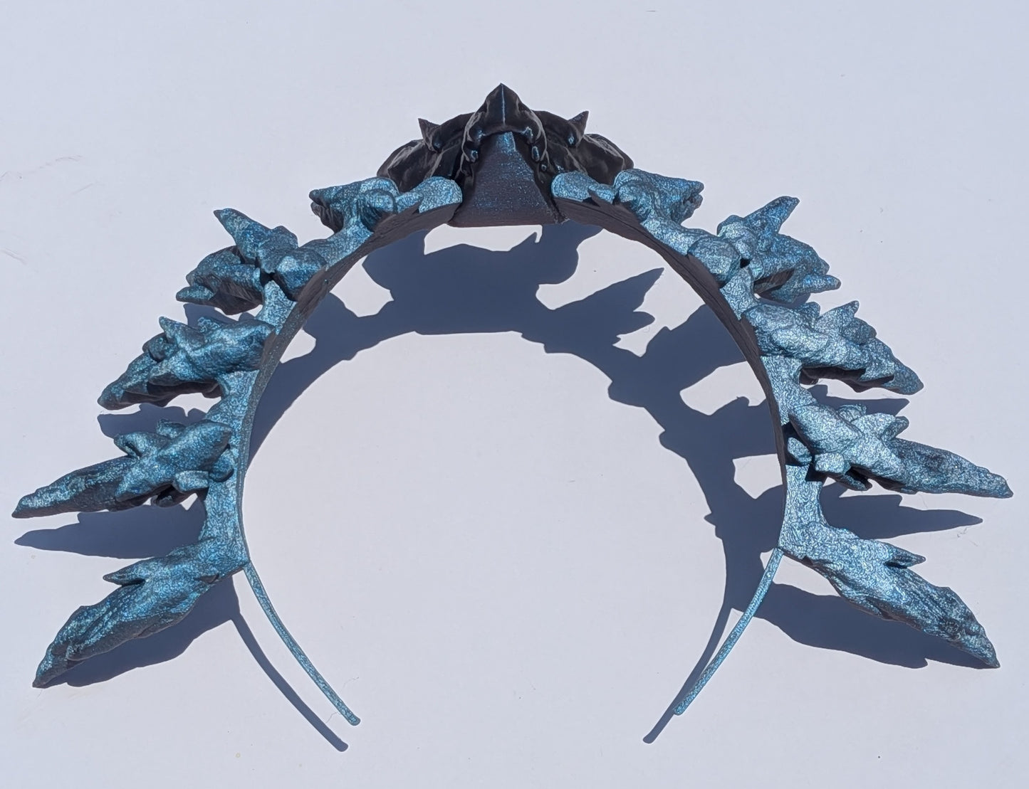 A metallic silver headband styled with icy blue and silver leaf-like spikes, photographed against a plain white background with a distinct shadow.