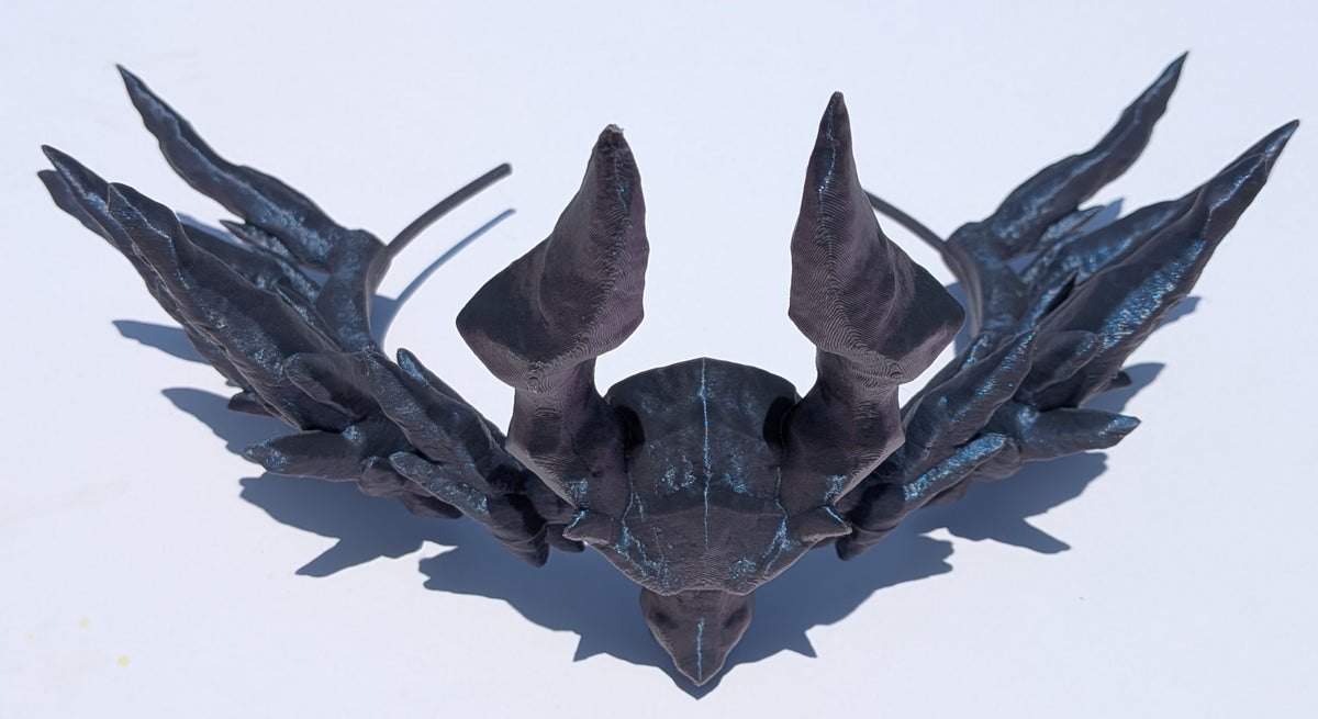 A dark metallic fantasy horned helmet or headpiece displayed on a plain white background, viewed from a top-down angle.