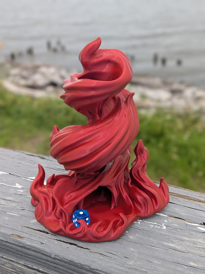 Flame dice tower outdoors on a wooden railing with a blue die in the tray
