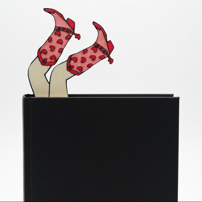 legs with cowgirl boots bookmark sticks out of black book with white background