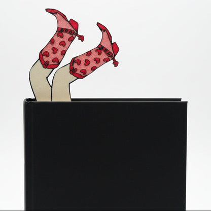 legs with cowgirl boots bookmark sticks out of black book with white background