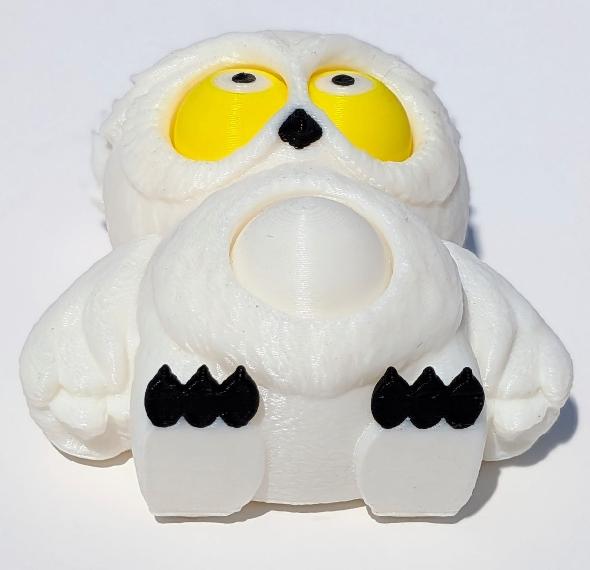 A white plush owl toy with large yellow eyes, black beak and claws, photographed on a plain white background.