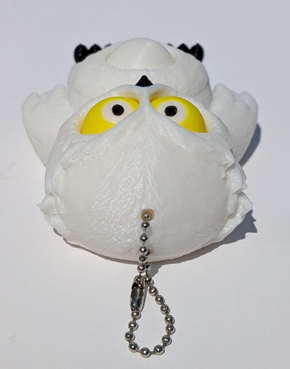 A white plush owl toy with large yellow eyes, black ear patches, and a silver ball chain keychain, photographed on a plain white background.
