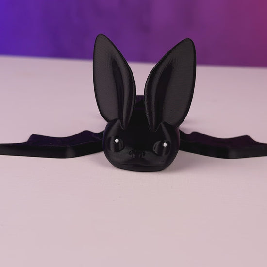 Black articulated bat fidget toy lying on its side with wings folded
