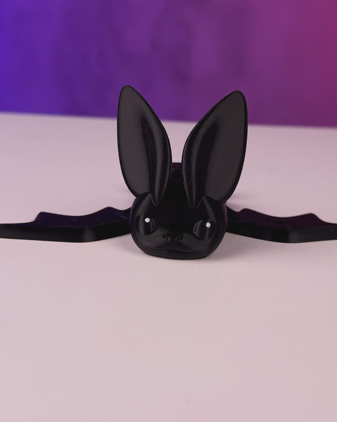 Black articulated bat fidget toy lying on its side with wings folded