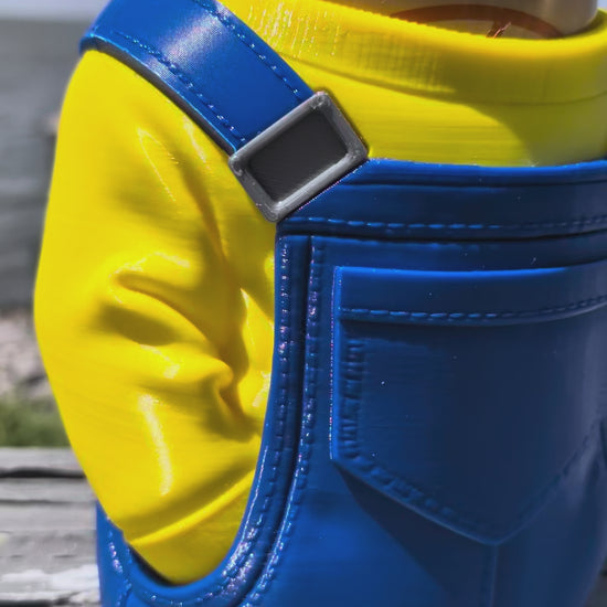 3D-printed can holder shaped like a yellow character in blue overalls, holding a soda can on a dock railing
