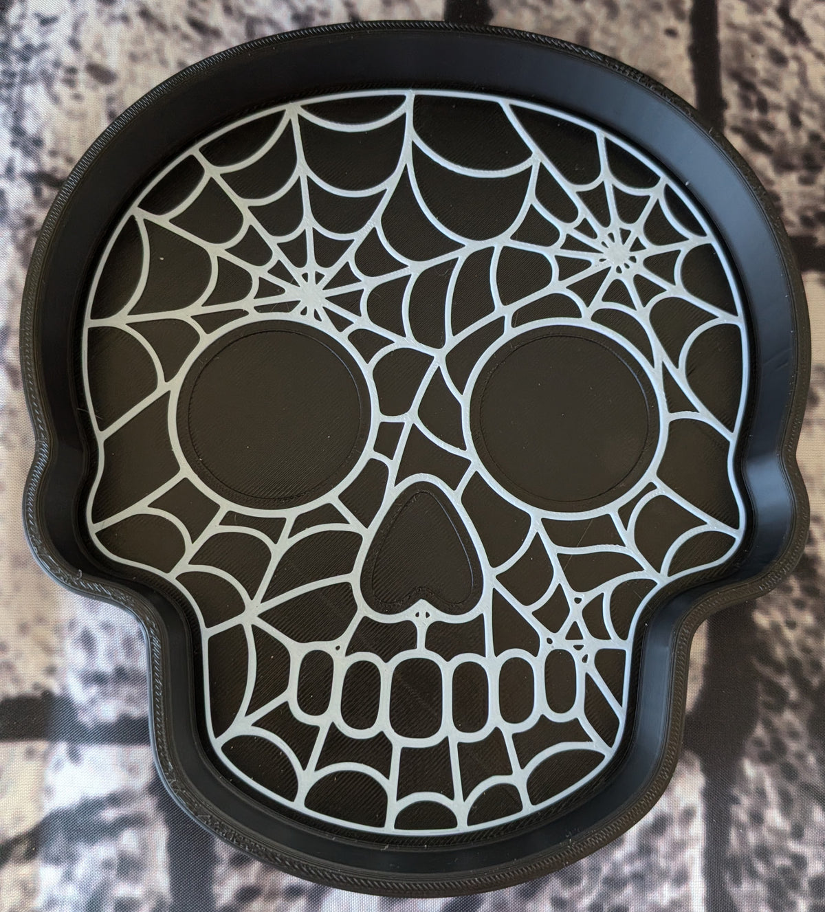 Skull-shaped trinket tray with spider web cutout and eye sockets, top view