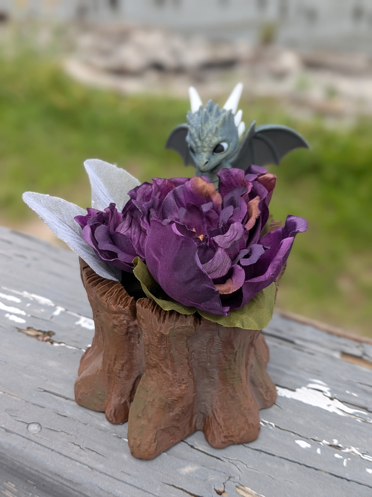 Dragon stump planter displayed outdoors on a wood railing