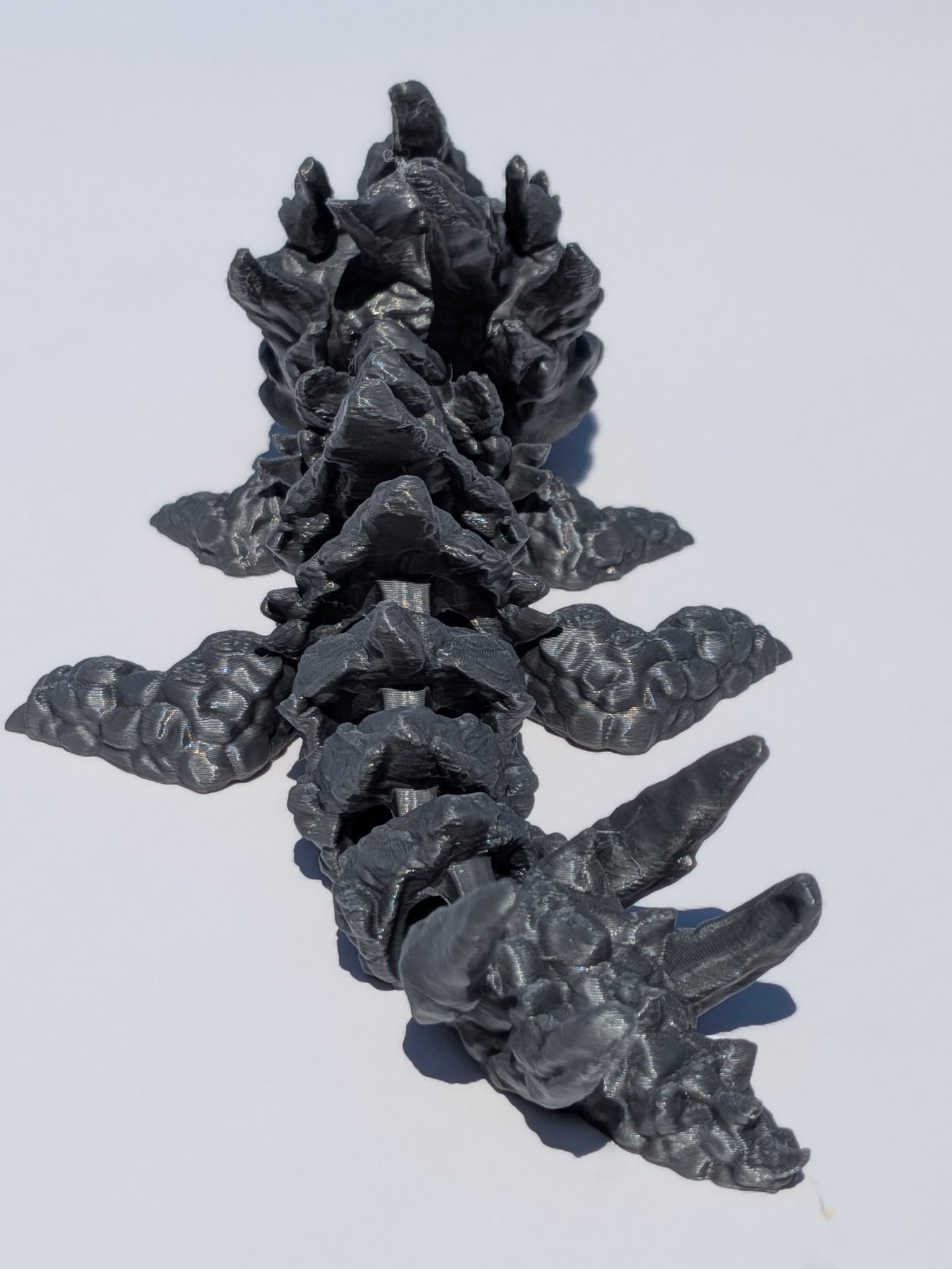 A dark gray 3D-printed articulated spine model, shown on a plain white background.