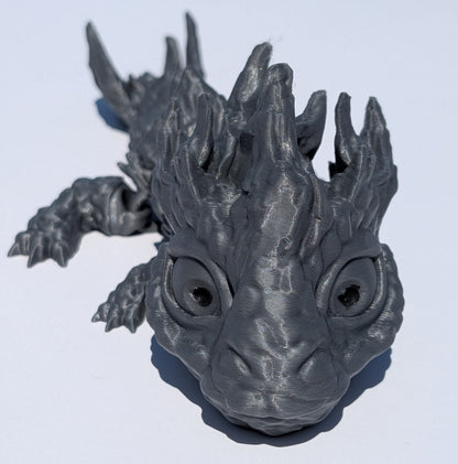 A 3D-printed dragon figurine in a matte dark gray finish, shown from a low angle on a plain white background.